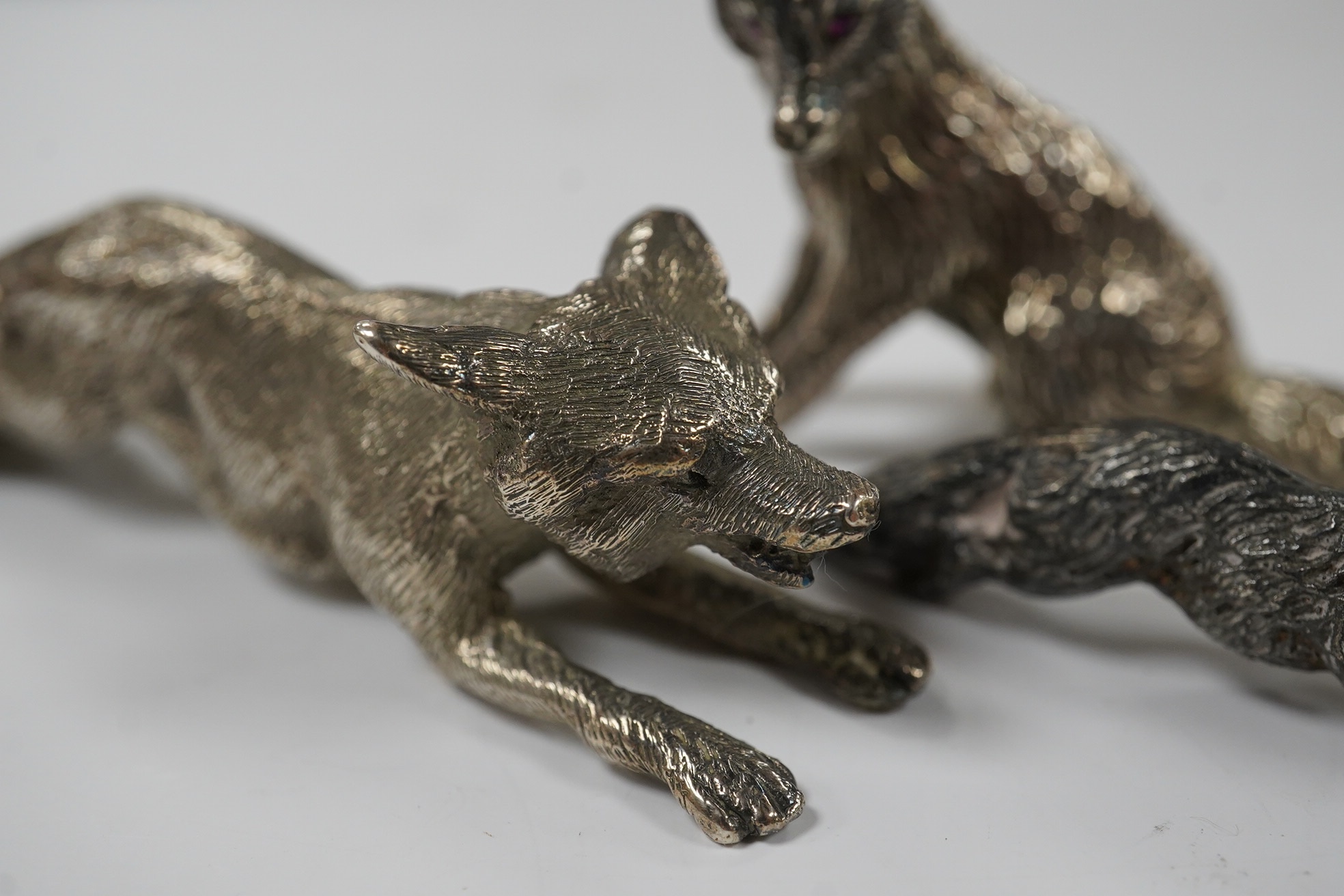 Two 1960's silver miniature models of a fox, both London, 1968, seated by Edward Barnard & Sons Ltd, height 38mm and one other smaller silver model of a running fox, 6.7oz. Condition - fair to good